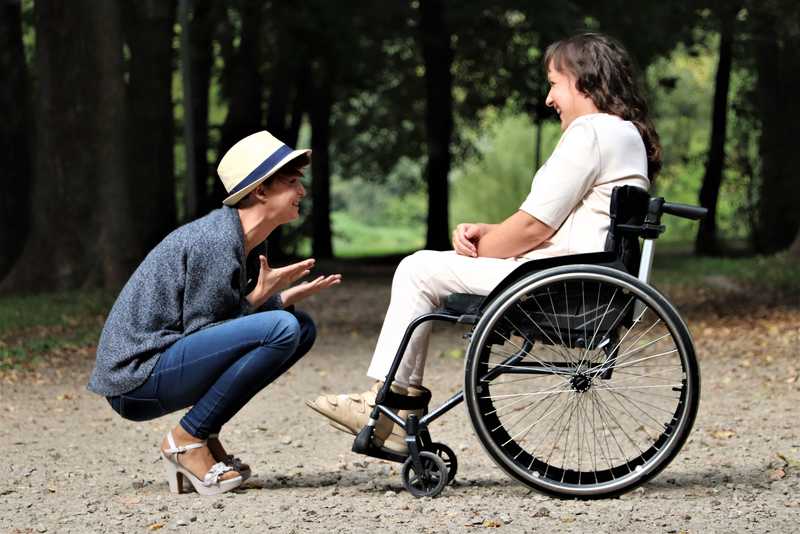 Frau im Rollstuhl spricht mit einer anderen Frau